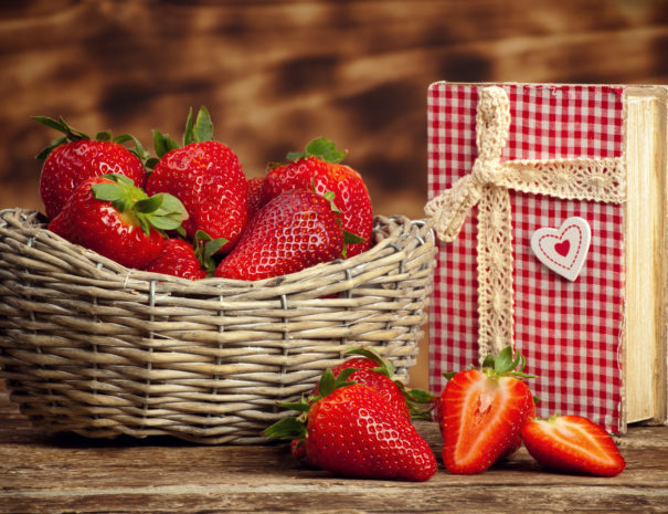 Beautiful strawberries with cookbook on wooden table